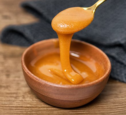 manuka honey drizzling in a wooden bowl photo