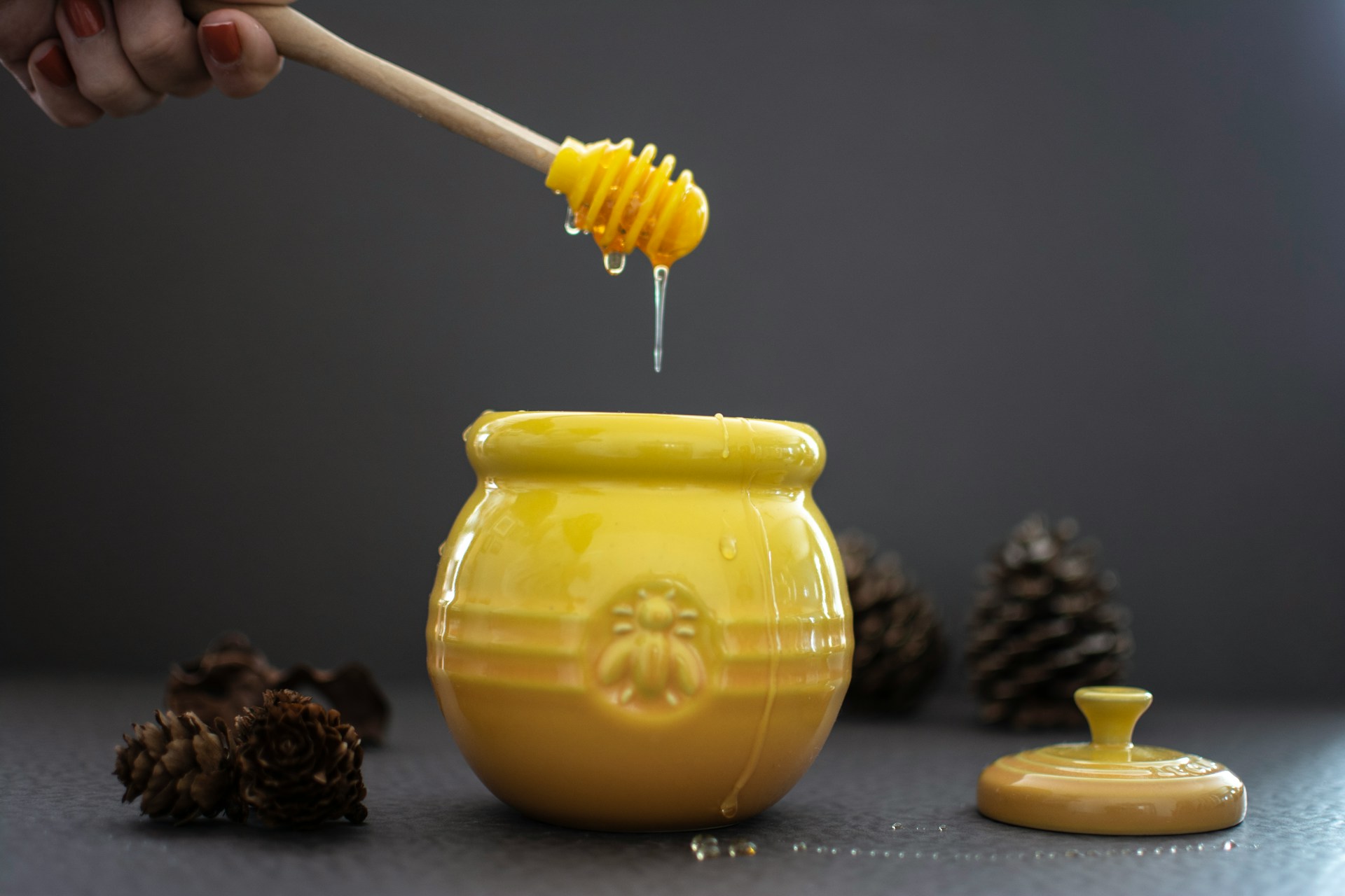Open yellow ceramic jar of honey